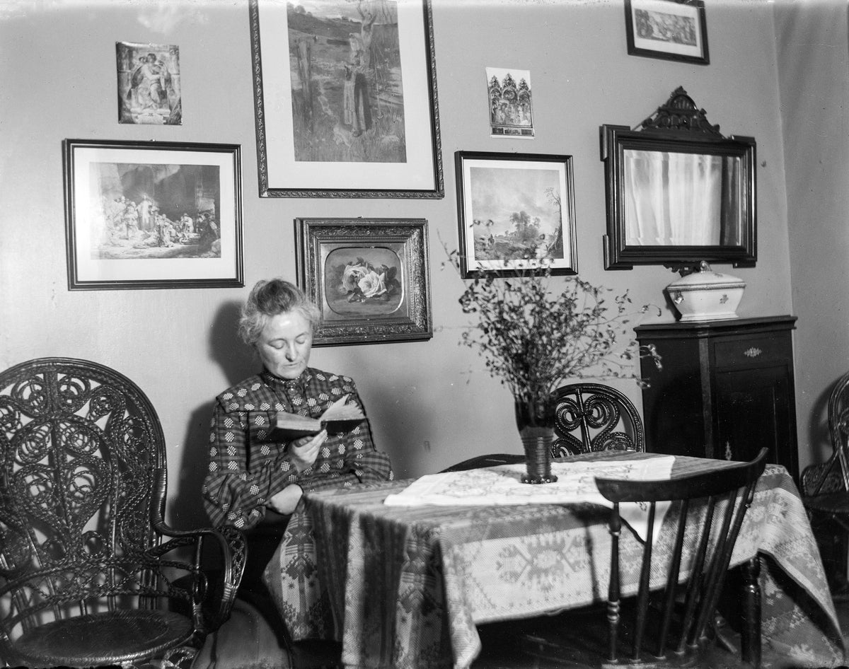 Kvinne leser ved spisebord.