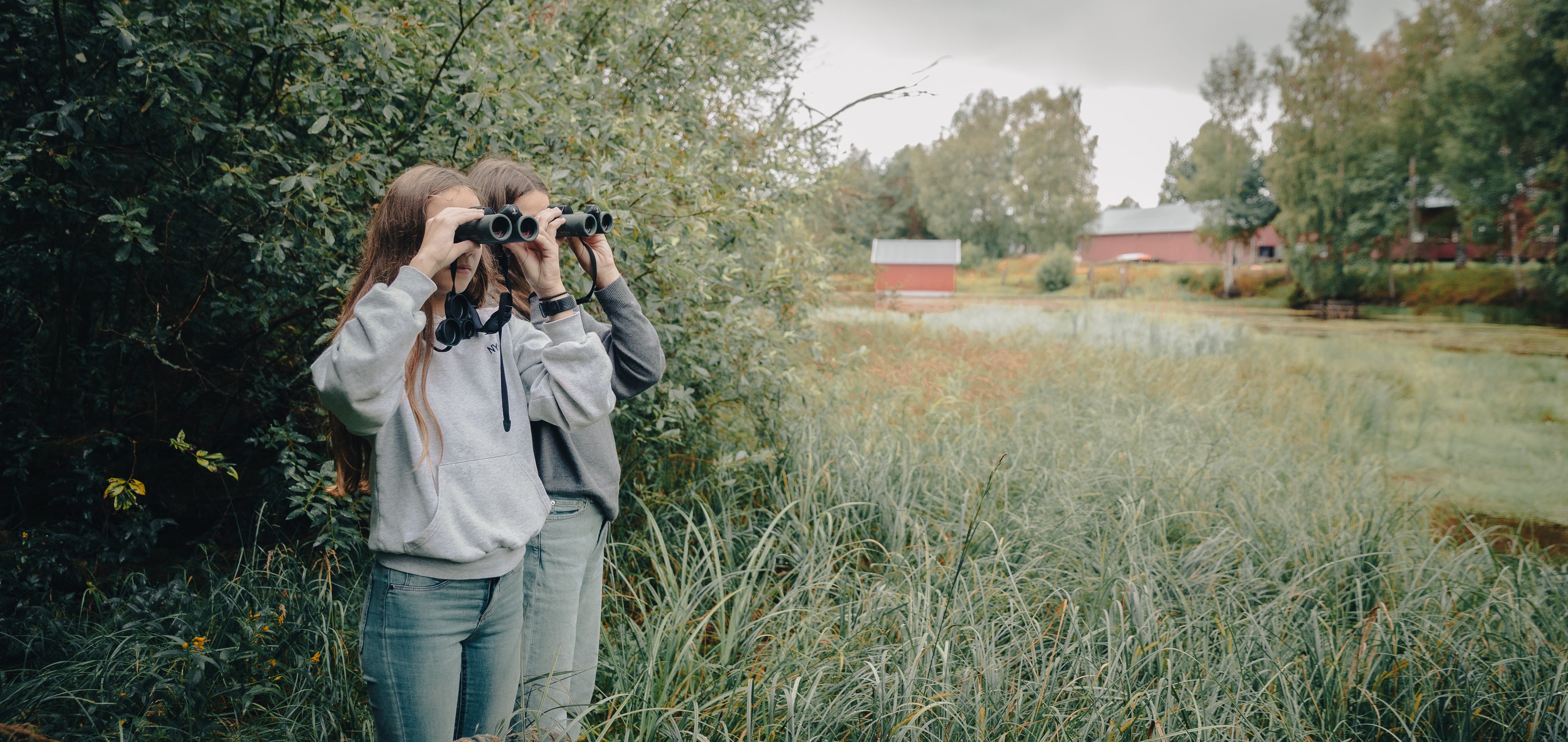 To jenter med kikkert i naturreservat.