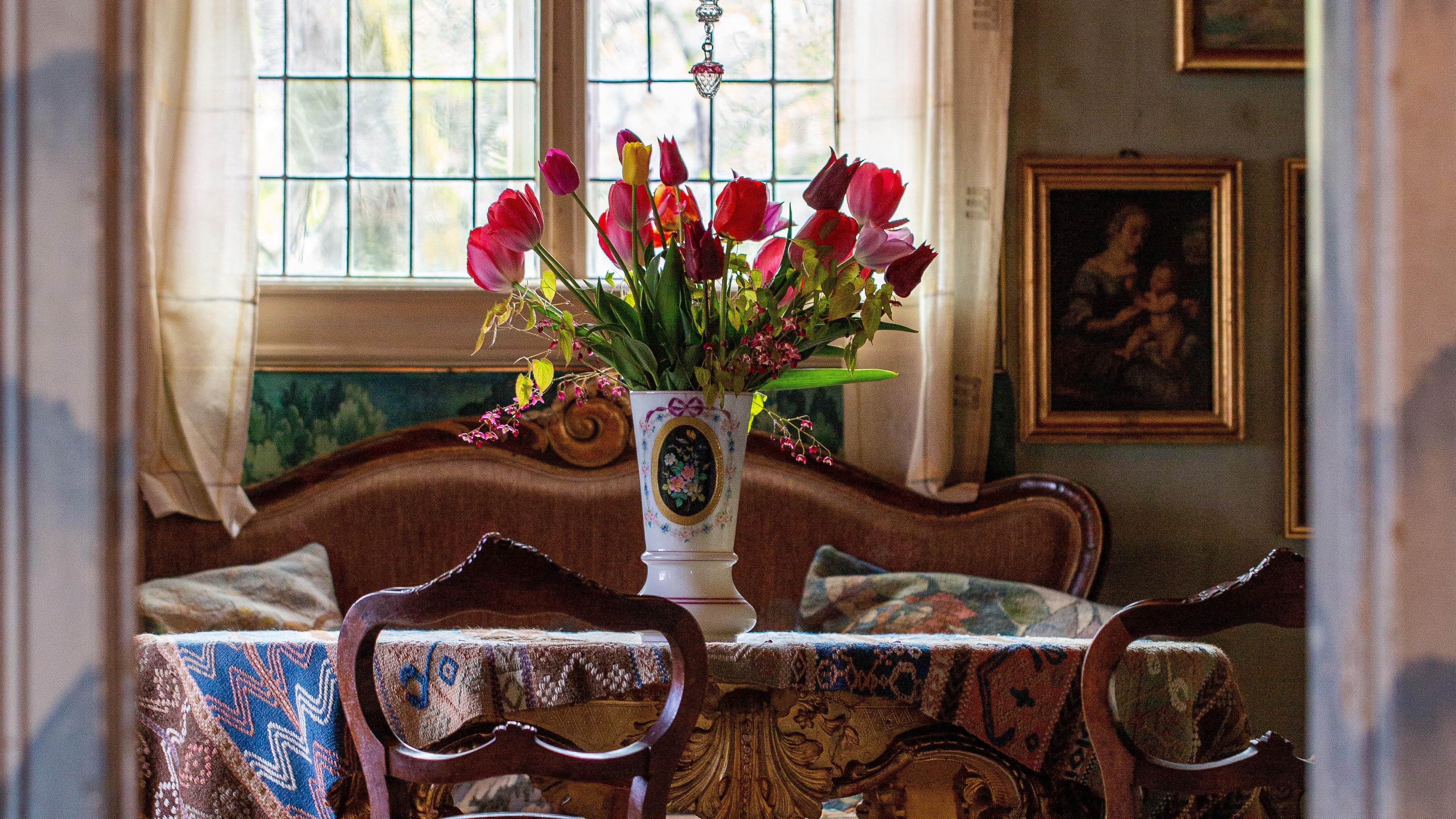 Blomstervase fylt med tulipaner står på et rundt bord i en stue.