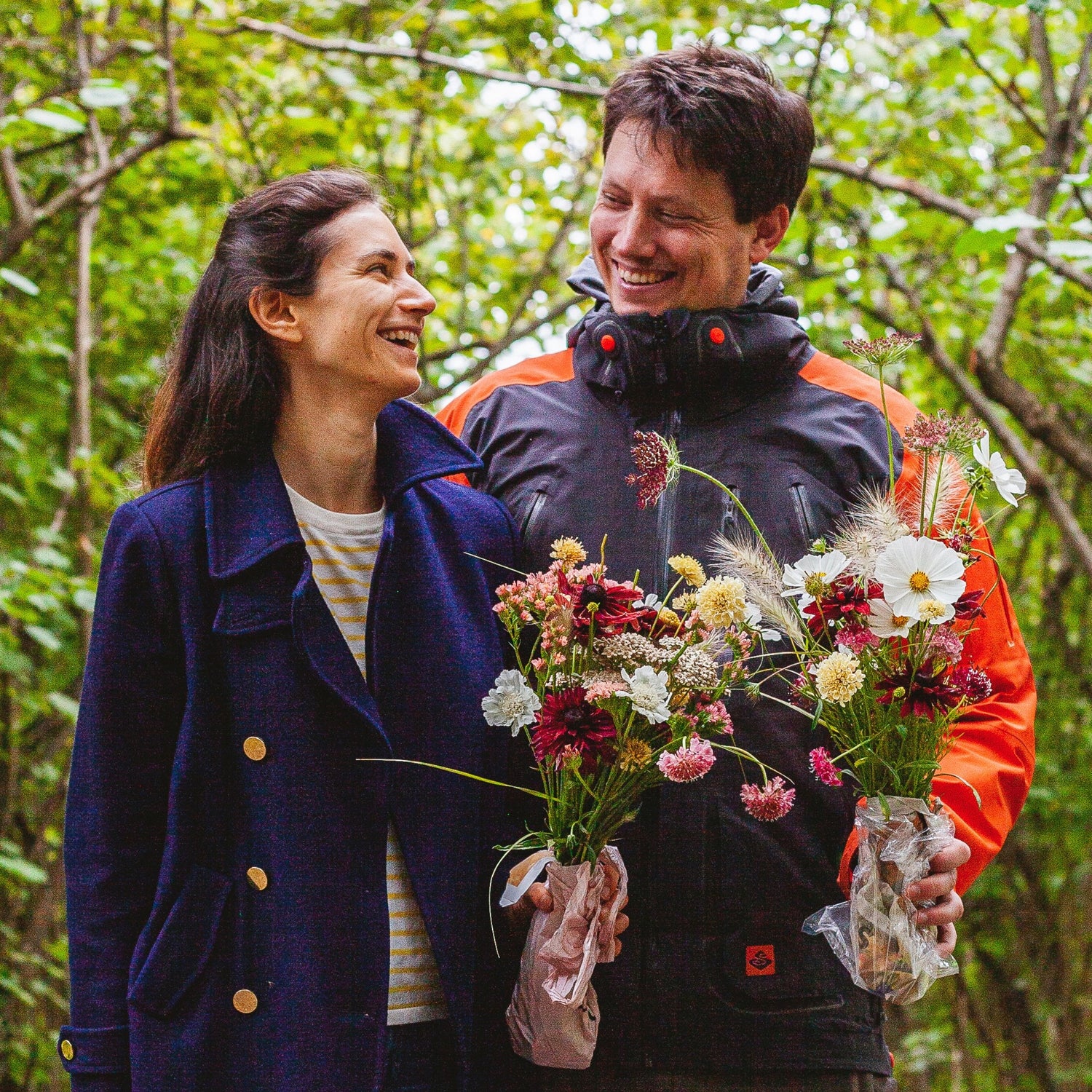 Mann og kvinne ser på hverandre mens de holder i hver sin blomsterbukett.